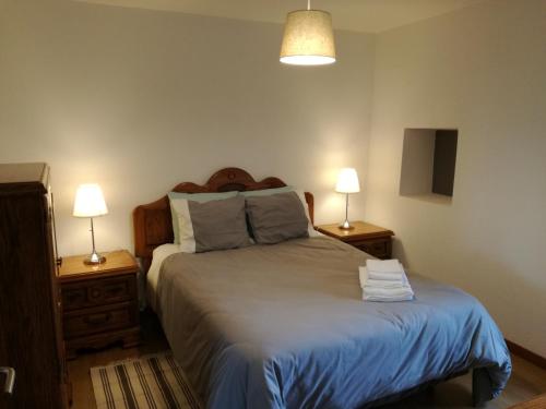 a bedroom with a bed with two night stands and two lamps at Casa de Paulus - Gerês in Geres