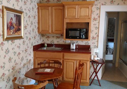 a kitchen with a sink and a table and a microwave at Thayers Inn in Littleton