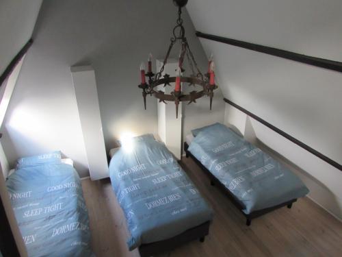 a room with two blue beds and a chandelier at De Spreekkamer in Hoogstraten