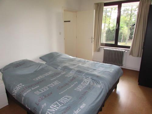 a bed with a blue comforter with writing on it at De Spreekkamer in Hoogstraten