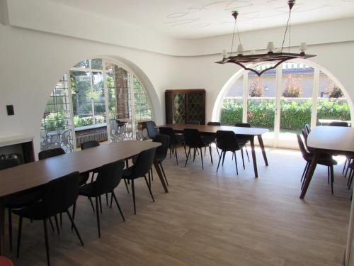 a dining room with tables and chairs and windows at De Spreekkamer in Hoogstraten