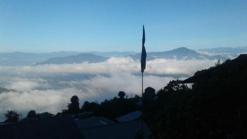uma bandeira no topo de uma montanha com nuvens em Vamoose Tashi Homestay em Rangpo