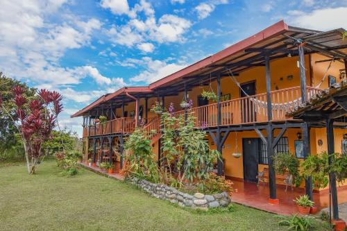 an orange building with a balcony and plants at Hotel Alto de los Andaquies in San Agustín