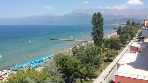 a beach with umbrellas and people in the water at Hotel Pogradeci in Pogradec
