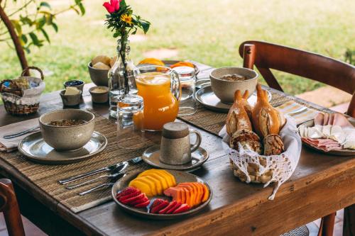 Amana Tiradentes في تيرادينتيس: طاولة خشبية مليئة بأطباق الطعام وعصير البرتقال