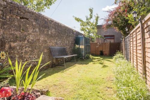 a bench in a garden next to a wall at Country Nest in Carnwath