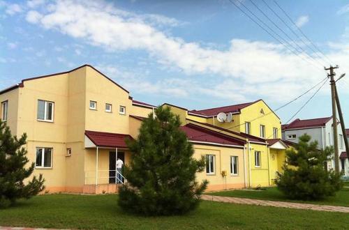 une maison jaune avec des arbres devant elle dans l'établissement " Na golubom ozere", à Kamianske