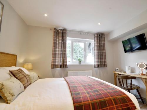 a bedroom with a bed and a desk and a window at The Cayley Arms Inn in Pickering