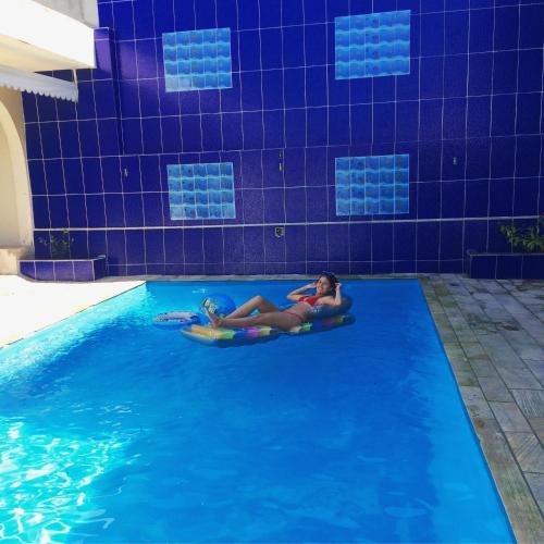 a woman laying on infogie boards in a swimming pool at Pousada Recanto do Mar in Saquarema