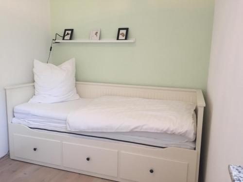 a bed with white sheets and pillows on it at Strandhaus Glowe in Glowe