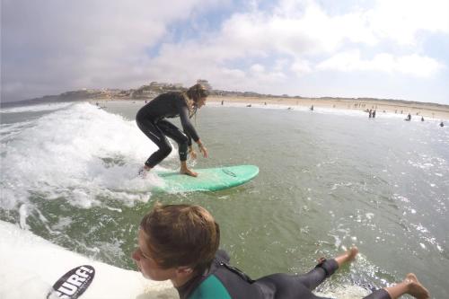 a woman riding a wave on a surfboard in the ocean at Vale de Lourinhã - Casas de Campo in Lourinhã