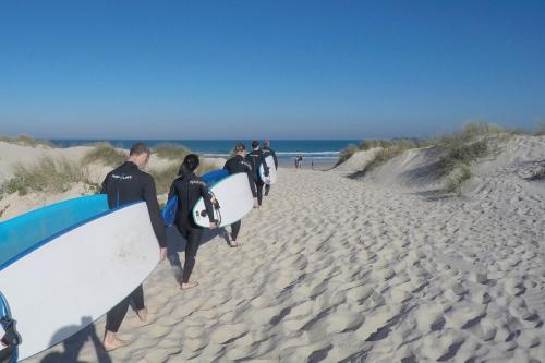 a group of people walking on the beach with surfboards at Vale de Lourinhã - Casas de Campo in Lourinhã