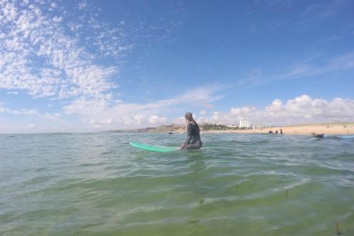 a man sitting on a surfboard in the ocean at Vale de Lourinhã - Casas de Campo in Lourinhã
