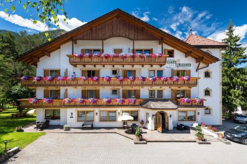 a building with a balcony with flowers on it at Hotel Resa Blancia in San Vigilio Di Marebbe