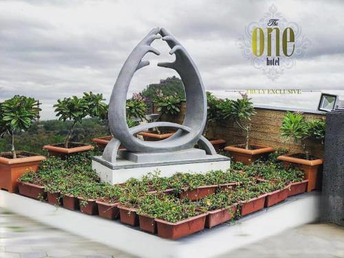 a statue in a flower bed with plants at The One Hotel in Aurangabad