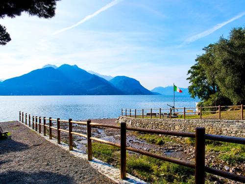 a fence next to a lake with mountains in the background at 7 Lake Sweet Home in San Siro