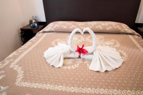 Dos toallas blancas se hacen para parecer corazones en una cama en Hotel Ross, en Morelia