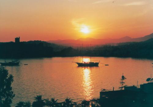 a boat on the water with the sunset in the background at Merhaba Pansiyon in Bodrum City