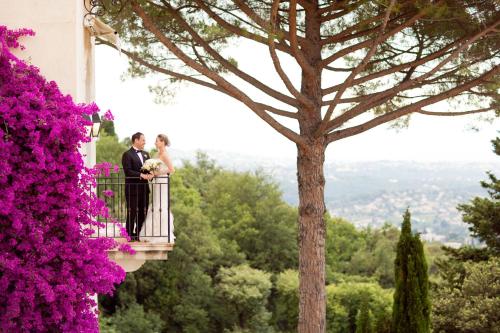 a bride and groom standing on a balcony with purple flowers at Château Saint-Martin & Spa, Oetker Hotels in Vence