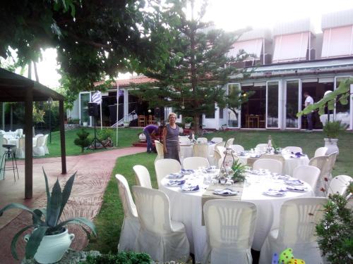 a woman standing at a table with white tables and chairs at Evoikos beach & resort in Livanátai