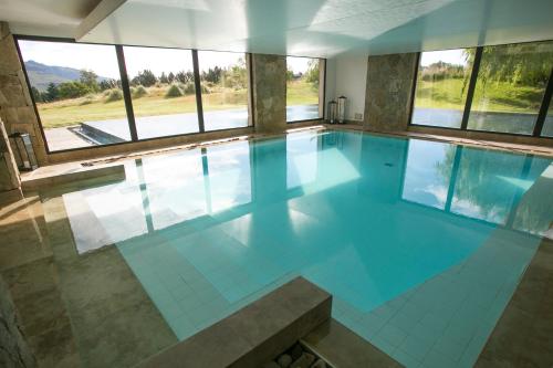a large swimming pool with blue tile floors and windows at Loi Suites Chapelco Hotel in San Martín de los Andes