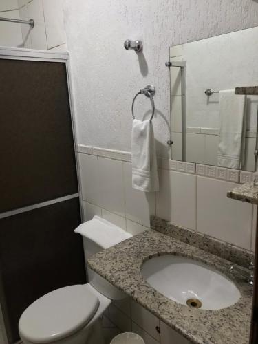 a bathroom with a toilet and a sink and a mirror at Bravo City Rondonópolis in Rondonópolis