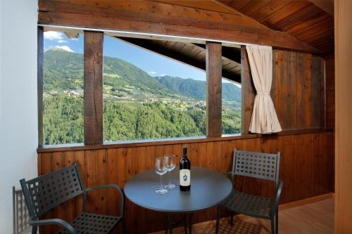 a table with a bottle of wine and two glasses at Sonnenhof in Rifiano
