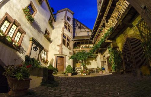 un edificio antiguo con un patio con macetas en ADRIHOF à Riquewihr, Cour de l'Abbaye d'Autrey en Riquewihr