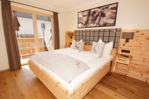 a bedroom with a large bed with white sheets at Kaiserappartements-Marie in Ellmau