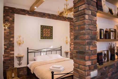Vinodorum Apartments في كيشيناو: غرفة نوم بحائط من الطوب وسرير
