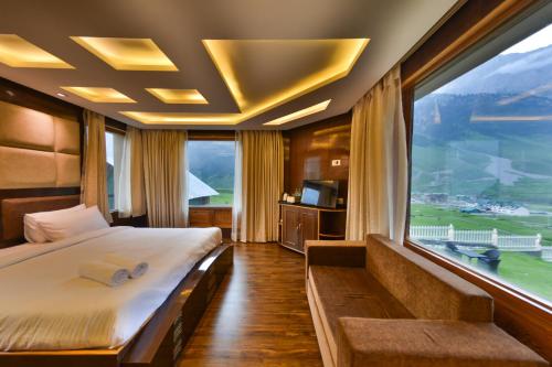 a bedroom with a large bed and a large window at Hotel Village Walk in Sonāmarg