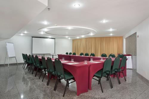 a conference room with a long table and green chairs at Scorial Rio Hotel in Rio de Janeiro