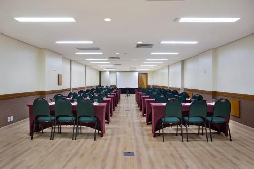 a conference room with tables and chairs and a white screen at Scorial Rio Hotel in Rio de Janeiro