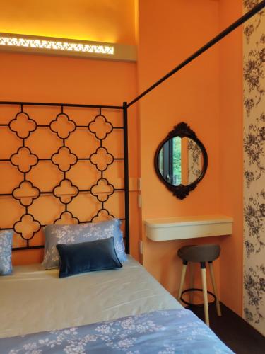 a bedroom with orange walls and a bed with a mirror at Teacher Cai Homeestay in Xiaoliuqiu