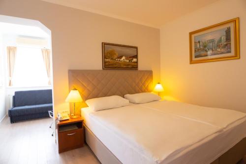 a bedroom with a large bed and a blue chair at Hotel Vila Tina in Zagreb