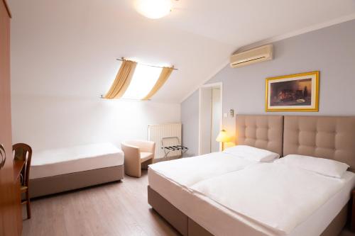 a hotel room with two beds and a chair at Hotel Vila Tina in Zagreb