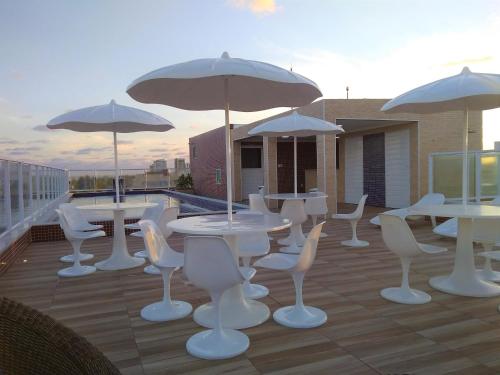 a group of tables and chairs with umbrellas on a balcony at Simas Praia Hotel in Aracaju