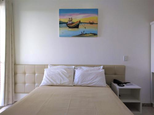 a bedroom with a bed with a painting on the wall at Simas Praia Hotel in Aracaju