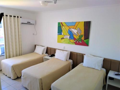 a room with two beds and a painting on the wall at Simas Praia Hotel in Aracaju