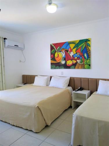two beds in a room with a painting on the wall at Simas Praia Hotel in Aracaju