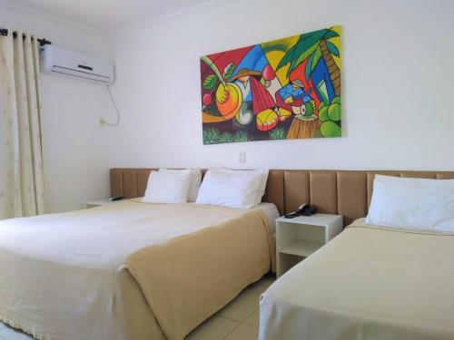 two beds in a room with a painting on the wall at Simas Praia Hotel in Aracaju