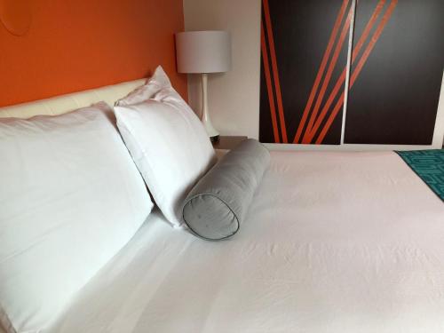 a white bed with two pillows on top of it at Howard Johnson by Wyndham Salem in Salem