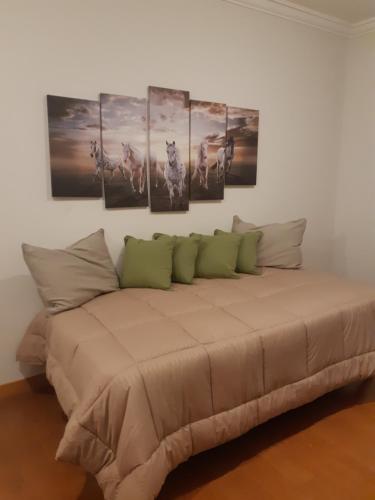 Habitación con cama con 4 cuadros en la pared en Magia III en Salta