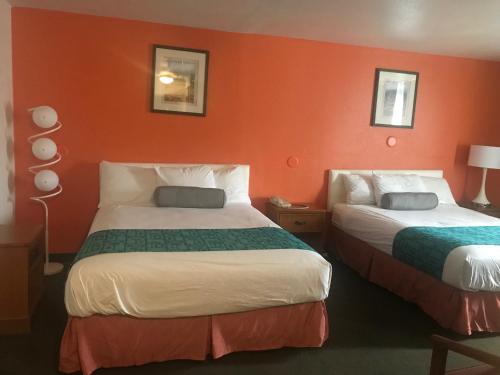 two beds in a hotel room with orange walls at Howard Johnson by Wyndham Salem in Salem