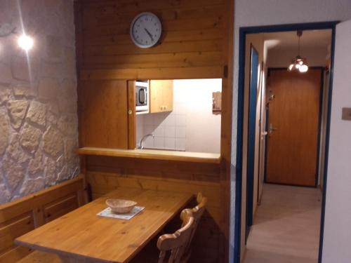 uma cozinha com uma mesa de madeira e um relógio na parede em Le Thabor em Valfréjus