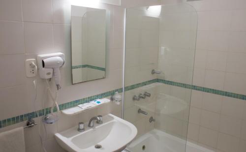 a bathroom with a sink and a tub and a mirror at Hotel Milton in La Paz