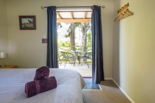 a bedroom with a bed and a balcony with a table at Hopewell Lodge in Kenepuru Sounds