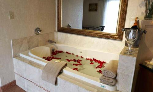 a bathroom with a bath tub filled with red flowers at Cedar Park Inn in North Stonington