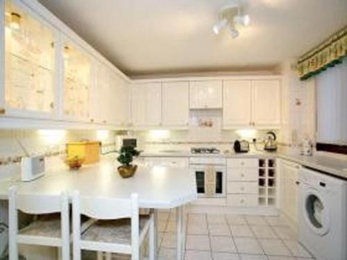 a white kitchen with a table and white cabinets at 3 bed room house in Aberdeen