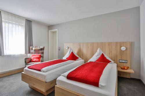 two beds in a hotel room with red pillows at Gasthof Restaurant Hirsch in Bad Ditzenbach